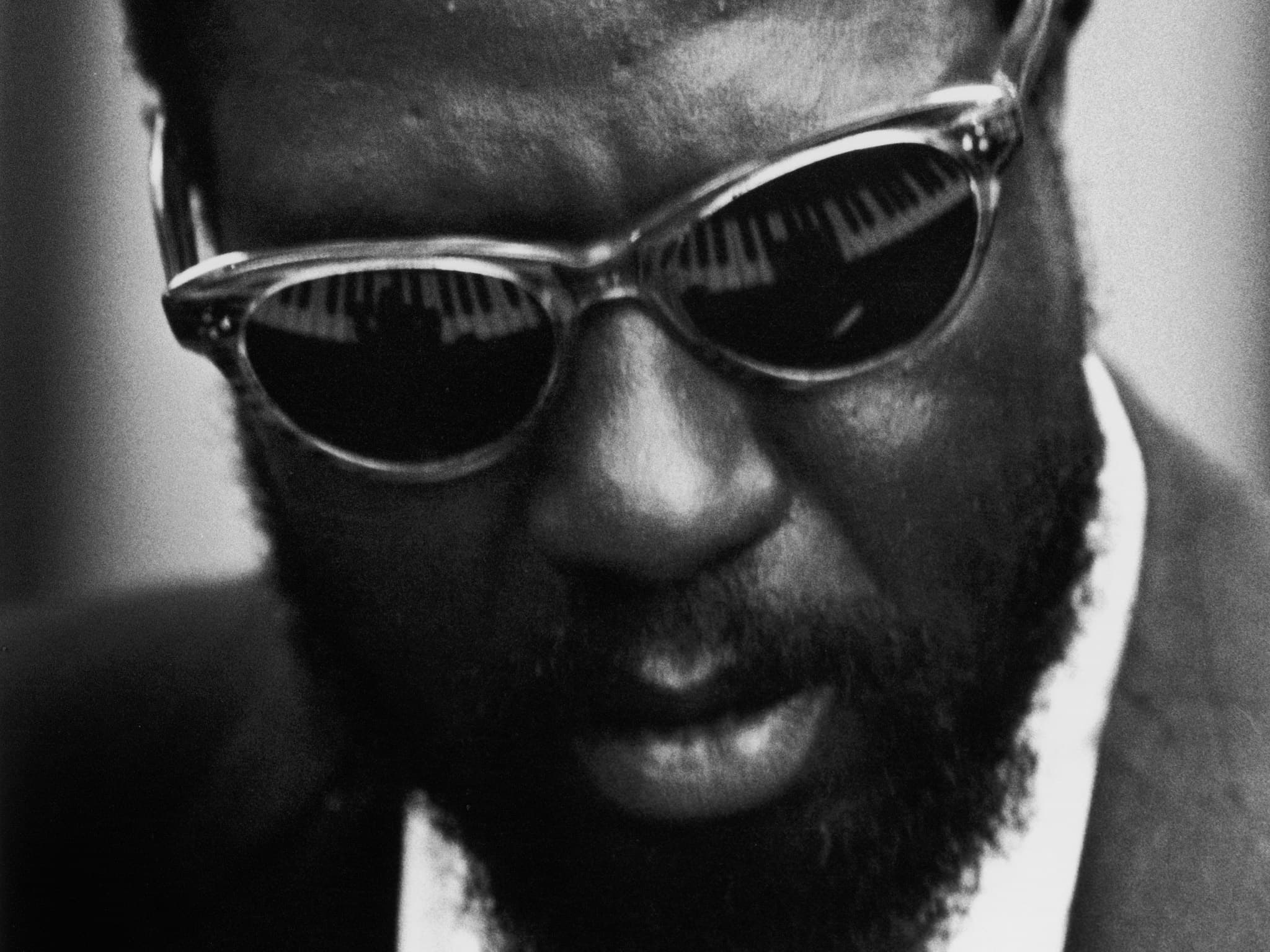 A person wearing sunglasses with piano keys reflected in the lenses.