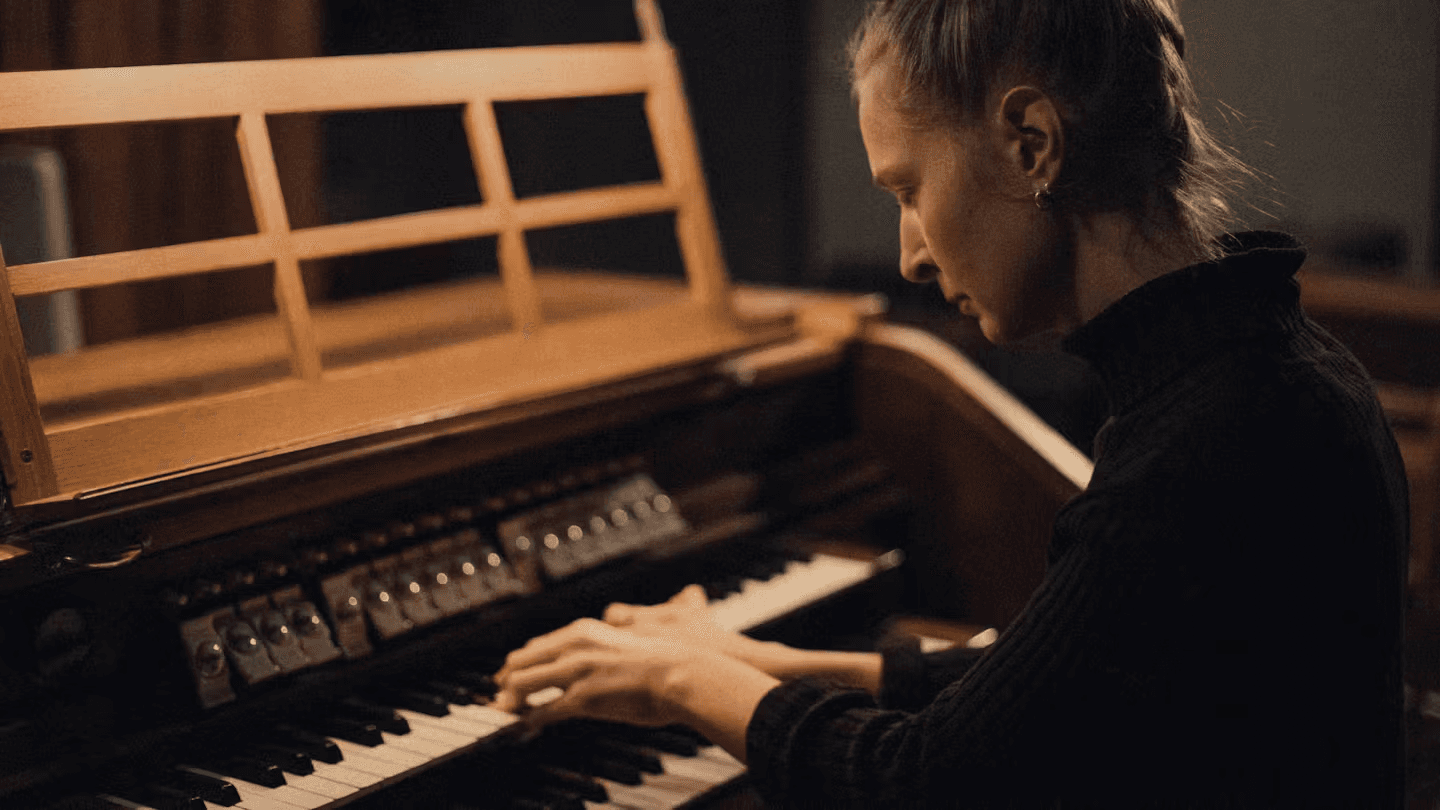 A person is playing an organ with a focused expression.