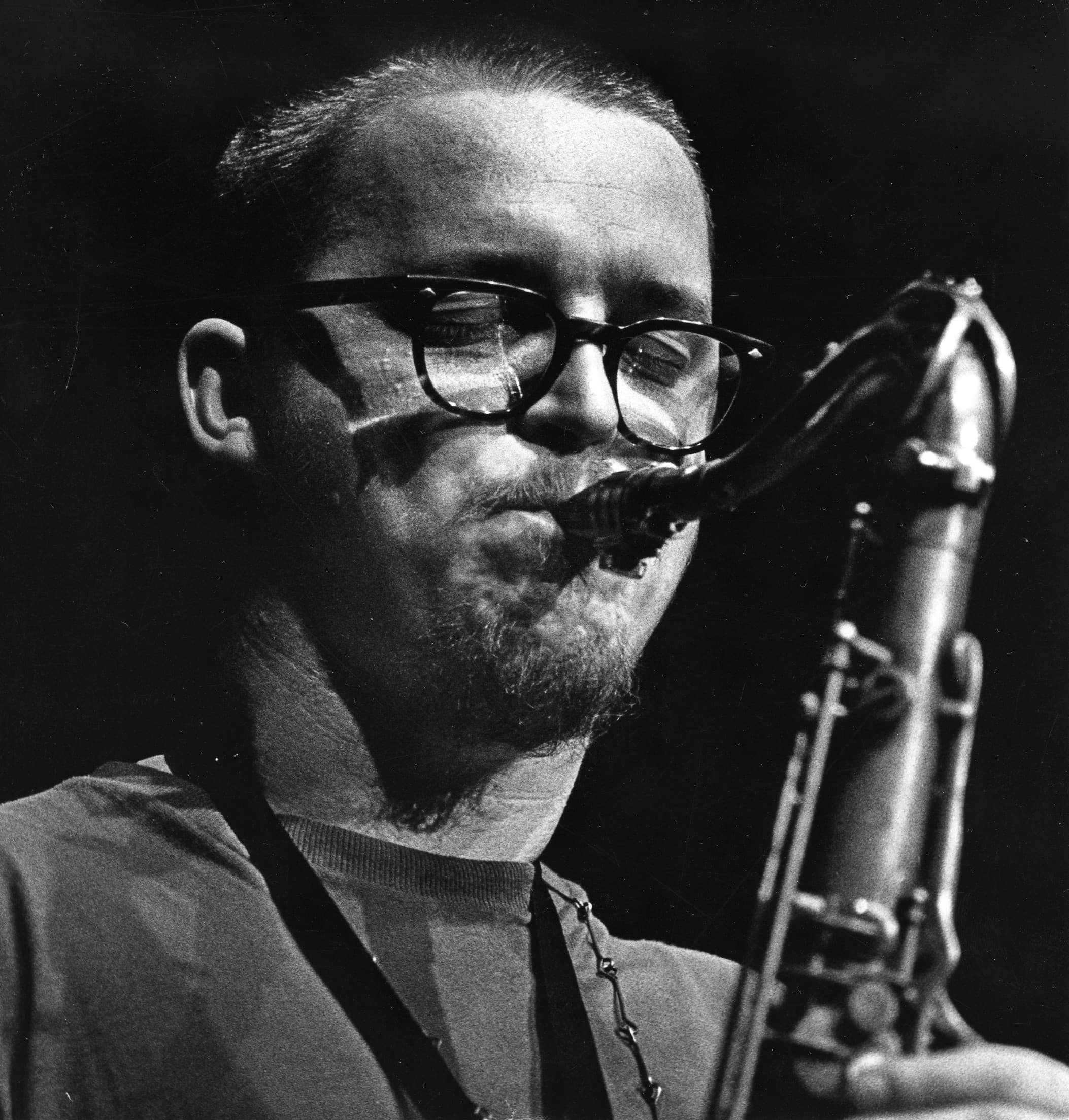 A person with glasses is playing a saxophone.