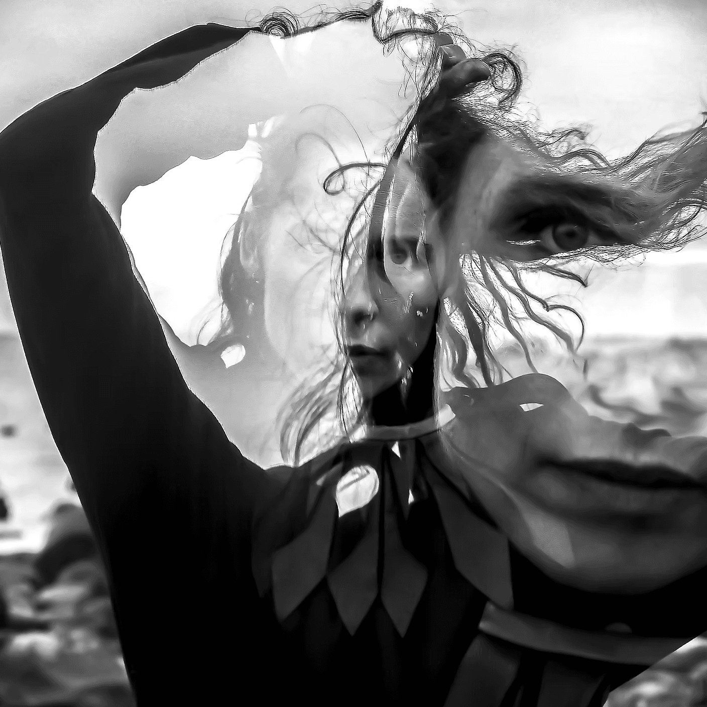 A black and white double exposure photograph of a woman's face and figure with flowing hair, creating a layered, surreal effect.