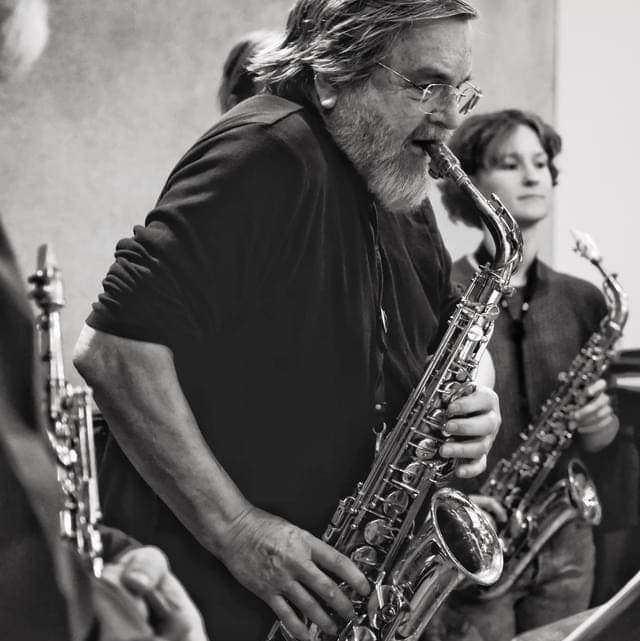 A group of musicians playing saxophones, with one prominently in the foreground.
