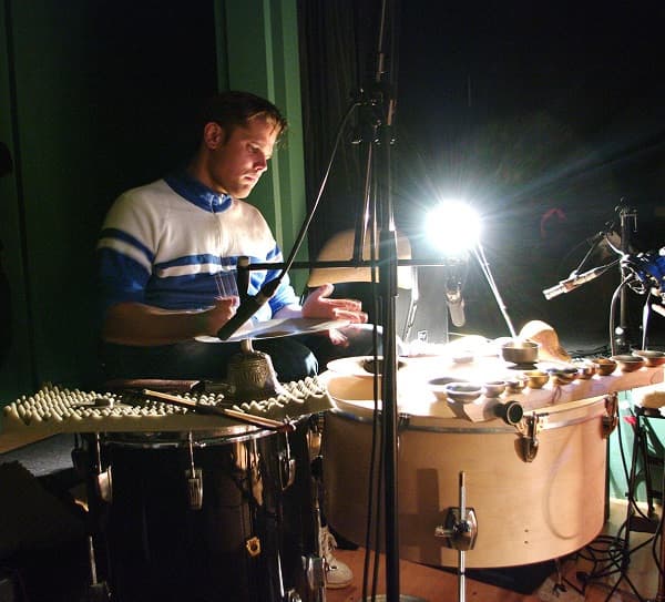 A person is playing a percussion instrument setup under bright lighting in a dark room.