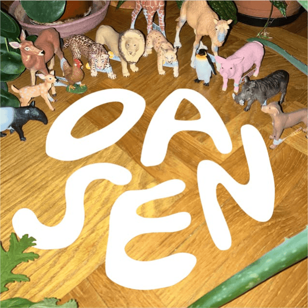 Toy animals are arranged on a wooden surface with large letters spelling "OASEN" in the foreground.